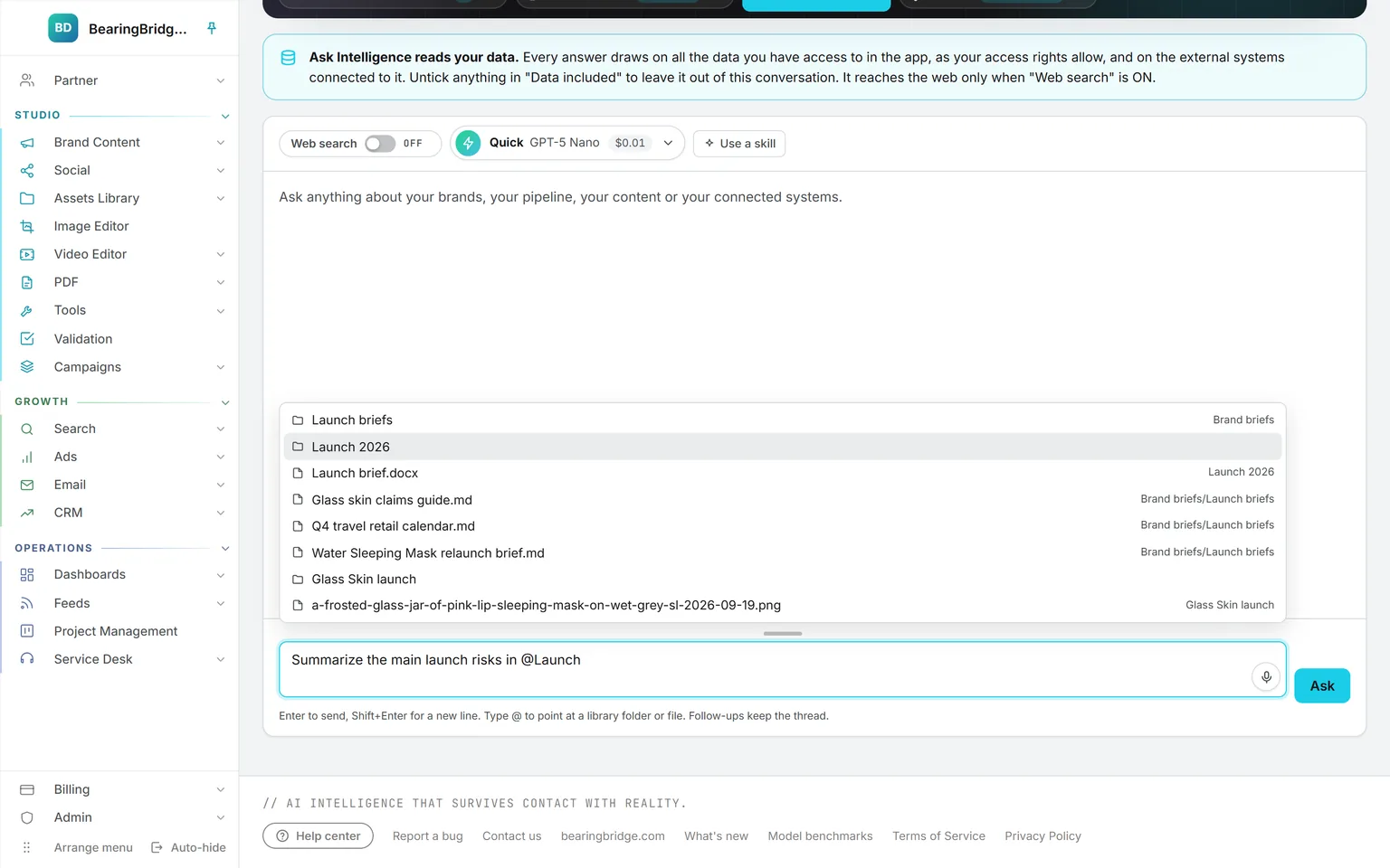 Typing @Launch in the Ask composer, with a dropdown listing the Launch 2026 and Launch briefs folders and their documents from the Assets Library
