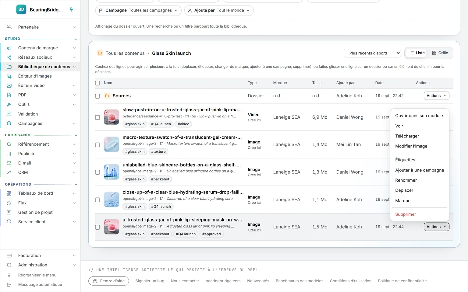 Les contenus du dossier de lancement Glass Skin : un sous-dossier, puis une vidéo et des images générées, chacune avec son moteur, son format, son prompt et ses étiquettes, et le menu Actions ouvert : ouvrir dans son module, voir, télécharger, modifier l’image, étiquettes, renommer, déplacer, marque, supprimer