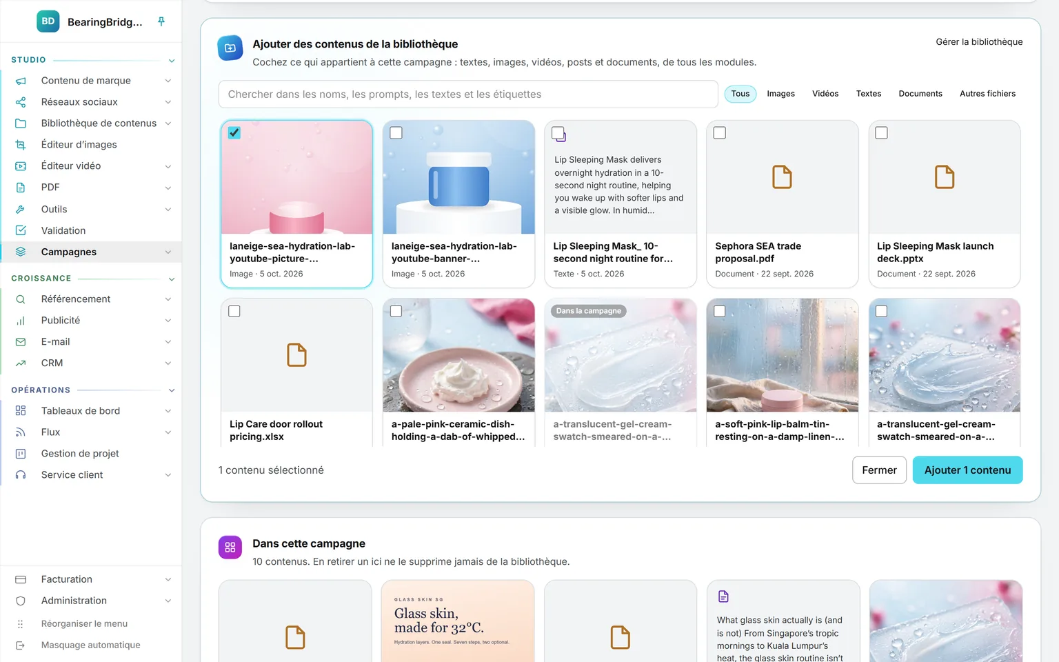 La fenêtre Ajouter des contenus de la bibliothèque ouverte sur une campagne : le champ de recherche, un filtre par type, dix contenus de la bibliothèque dont une image cochée et une autre signalée comme déjà présente dans la campagne, et le bouton Ajouter 1 contenu