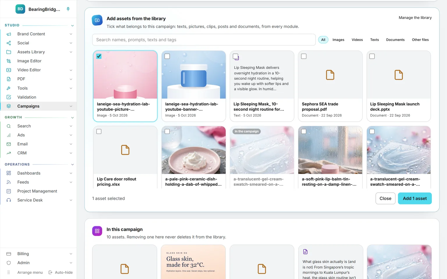 Add assets from the library open on a campaign: the search box, a filter per type, ten assets of the library with one picture ticked and one already marked as in the campaign, and the Add 1 asset button