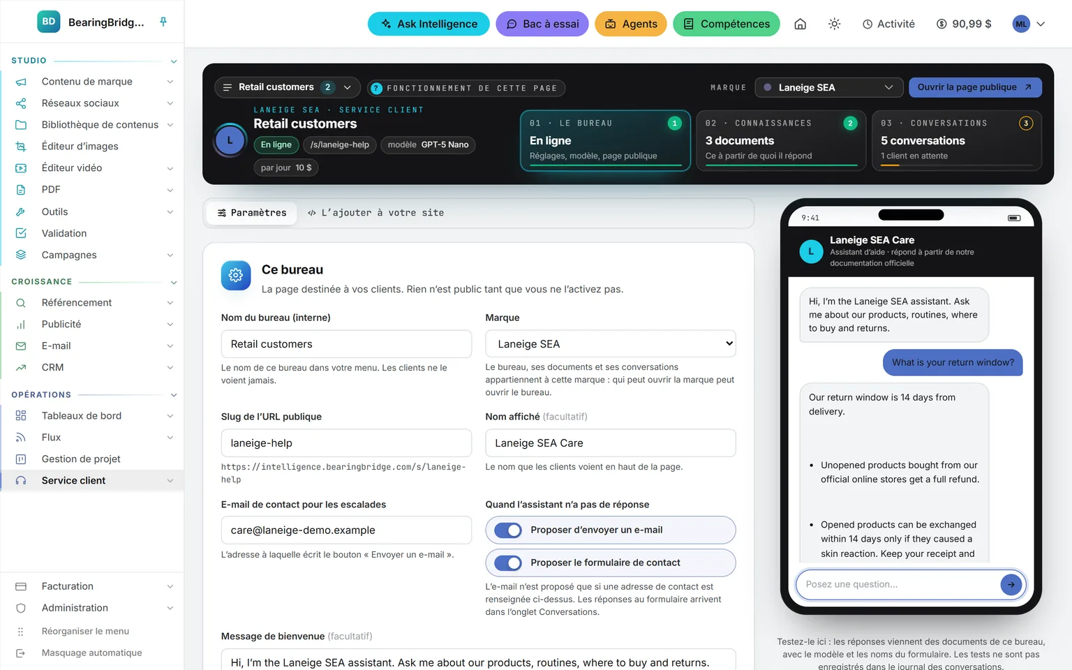 Les paramètres d’un bureau : son nom et sa marque, l’adresse publique, le nom affiché, l’e-mail de contact, les deux interrupteurs qui proposent un e-mail ou le formulaire de contact quand l’assistant n’a pas de réponse, et le message de bienvenue ; dans le bandeau au-dessus, l’état En ligne, le modèle et le budget quotidien ; à côté, un téléphone qui vient de répondre à une question test sur le délai de retour